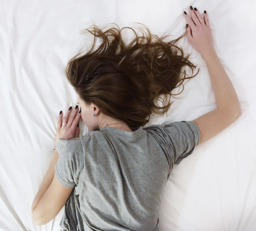 Woman sleeping on stomach on white sheets
